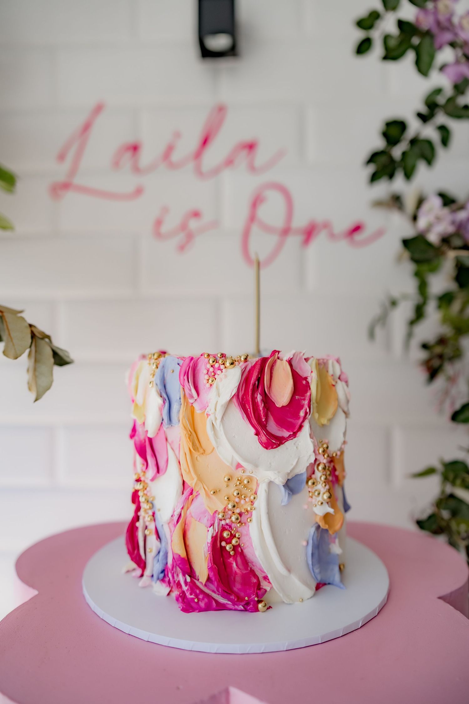 First birthday cake with watercolor frosting design in pink and white.