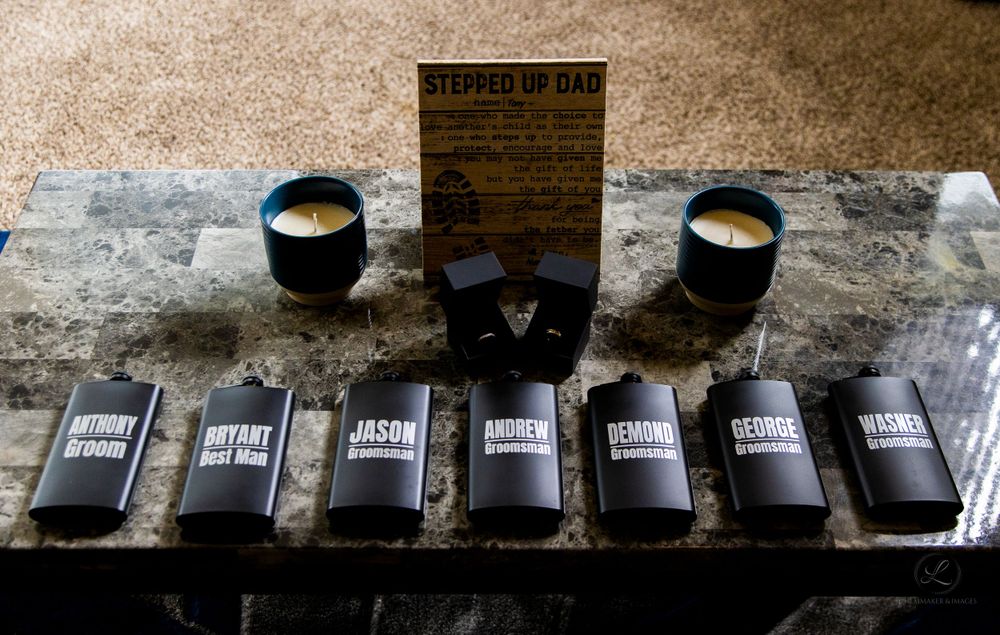 Black wedding favor boxes and candles arranged on a stone surface.