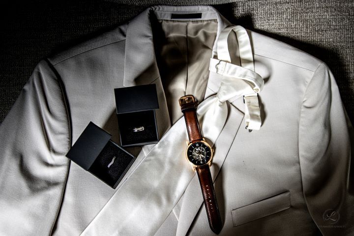 White formal suit jacket with accessories and brown leather watch.