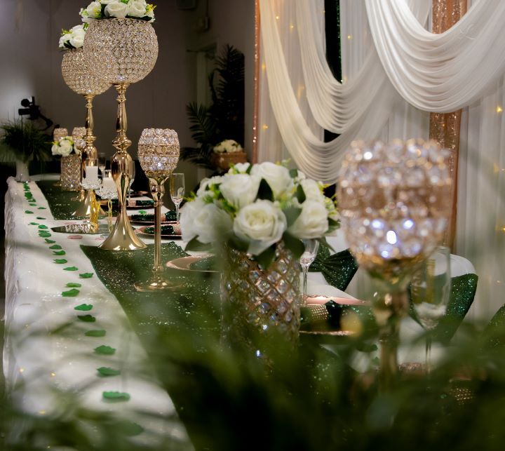 Elegant wedding table decor with crystal candelabras, white floral arrangements and draped fabric backdrops.