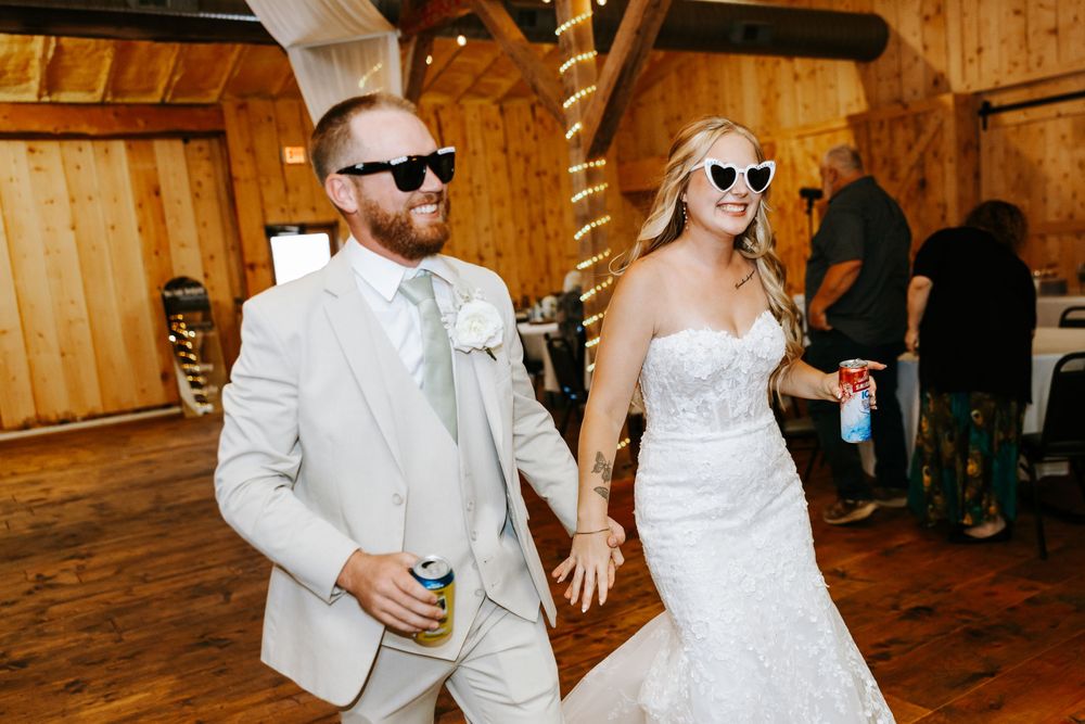 Wedding party dancing and celebrating in a rustic wooden barn venue with warm lighting.