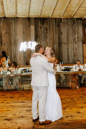 A couple shares their first dance together in a rustic wooden barn venue during their wedding reception.