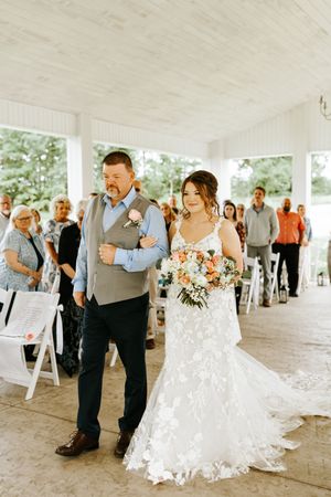 Couple dances together under a white tent during their outdoor wedding reception.