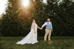 A couple walking hand in hand through a garden at sunset with sun flares illuminating the romantic scene.