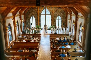A beautiful wooden church chapel interior with stained glass windows and rows of pews bathed in warm natural light.