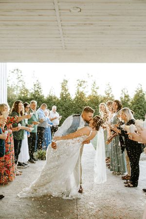 Wedding guests shower the newlyweds with confetti during an outdoor celebration.