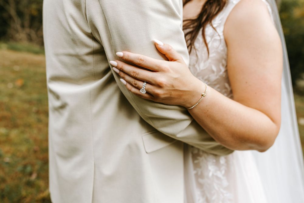 Close-up detail of white lace wedding dress fabric and delicate sleeve details in natural lighting.