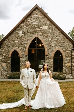 Stone church exterior serves as backdrop for elegant wedding portraits in natural lighting.