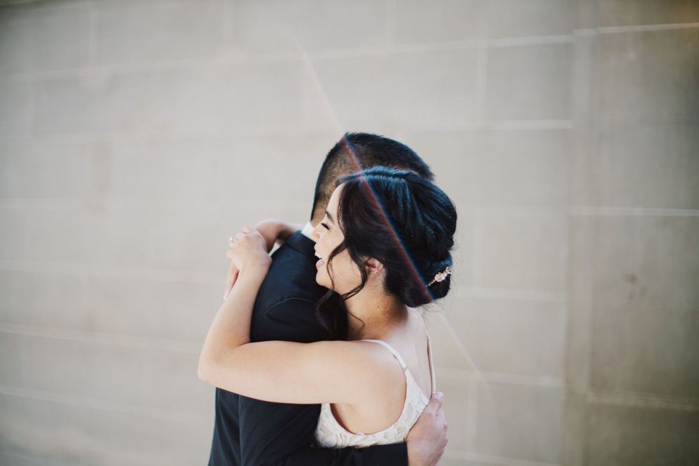 A tender embrace captured in soft focus against a neutral wall.