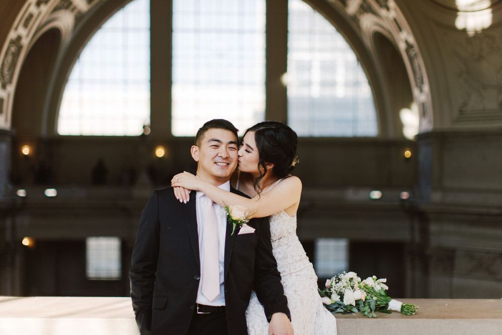 Intimate moment between newlyweds under grand architectural arch with decorative details.