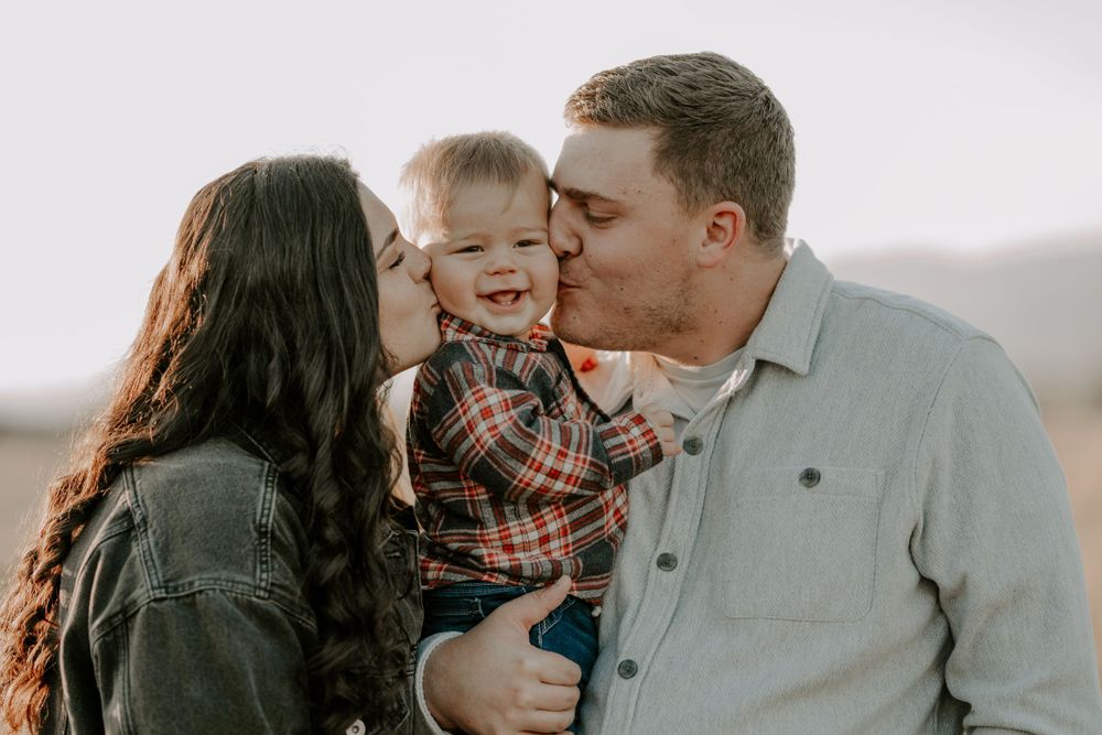 Family sharing a tender moment outdoors with their small child.