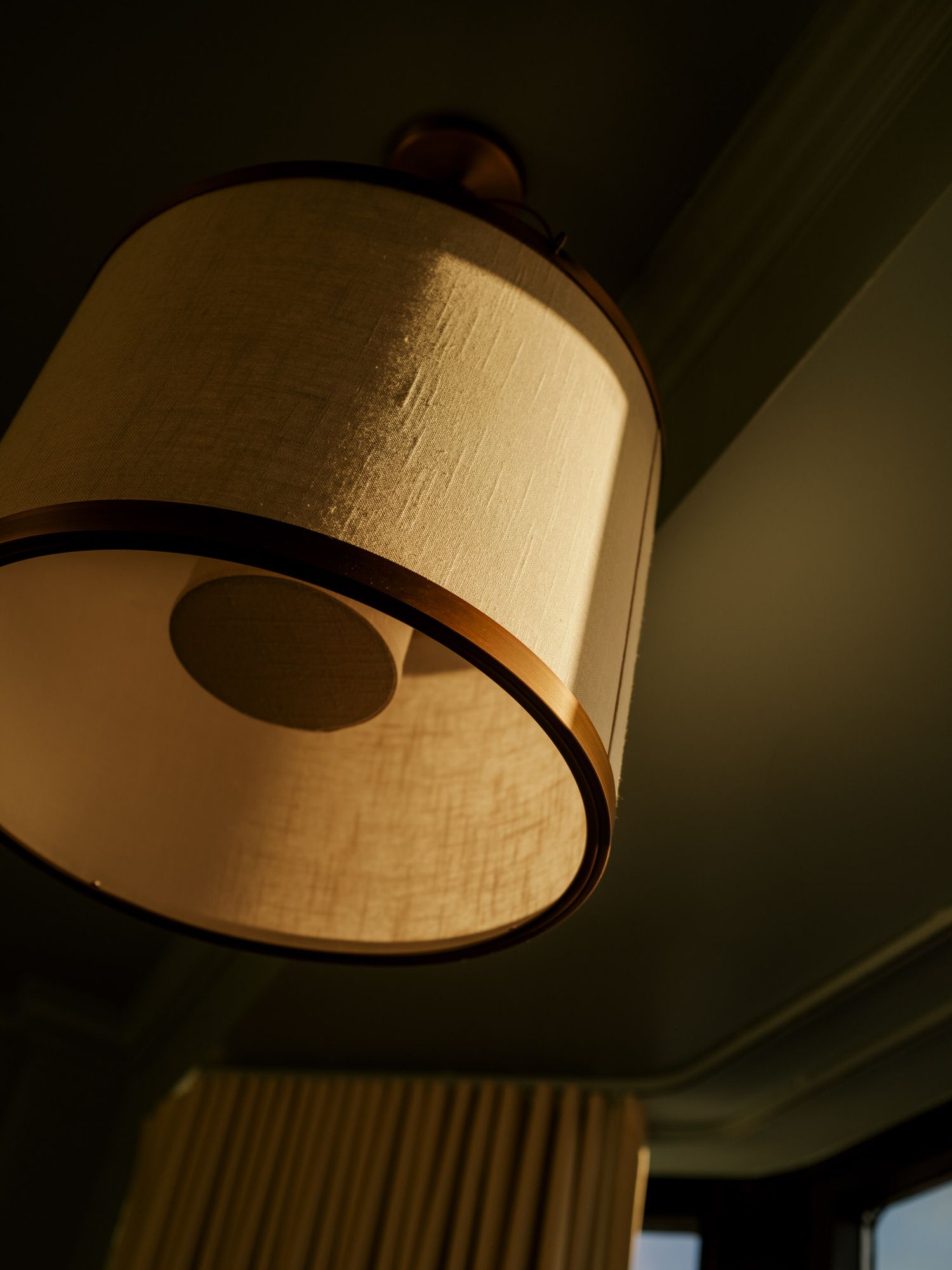 A warm-toned lampshade casts a soft glow in a dimly lit room, creating a cozy ambiance.