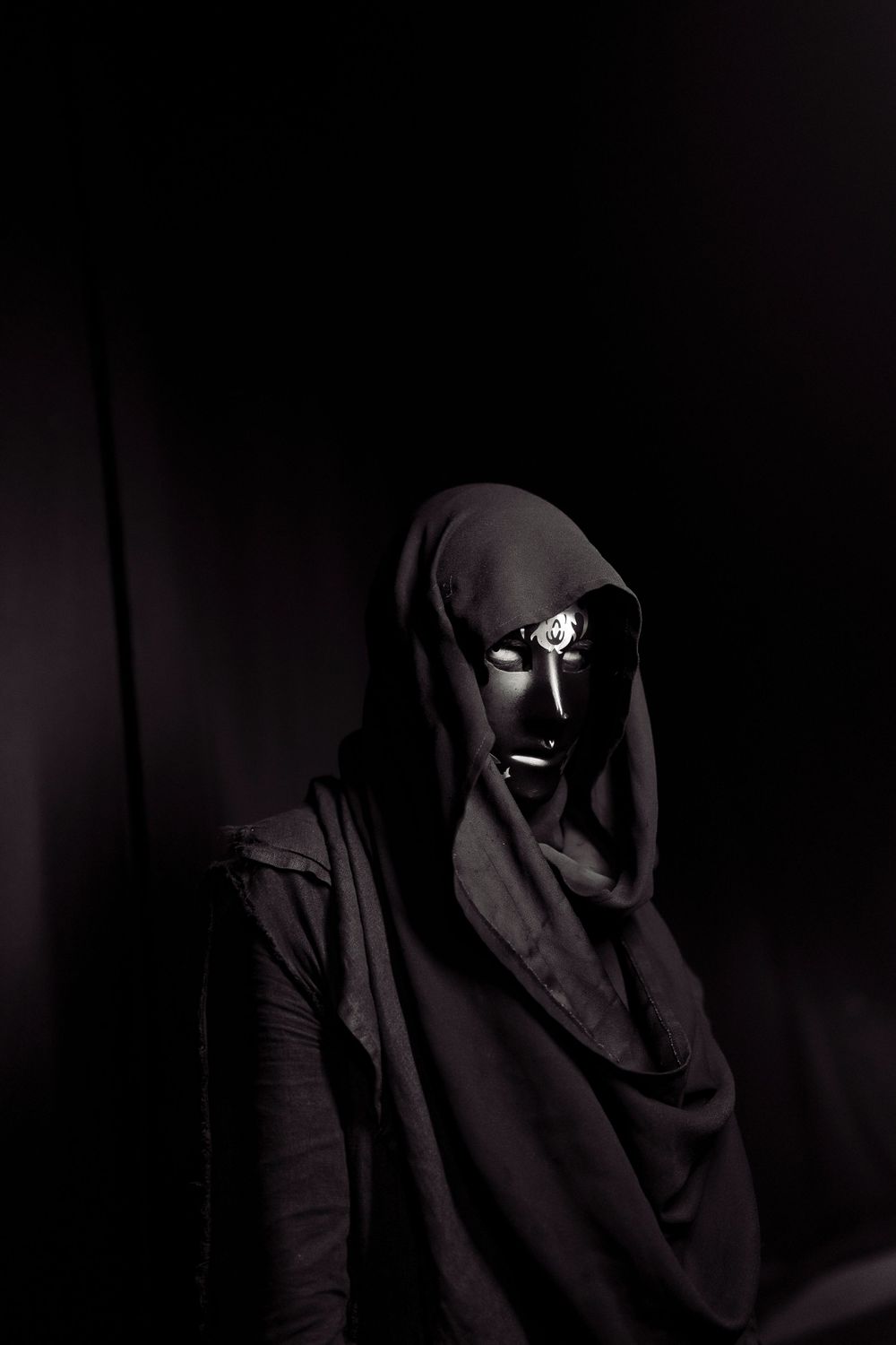 Dark silhouettes in hooded clothing against black background create mysterious atmosphere.