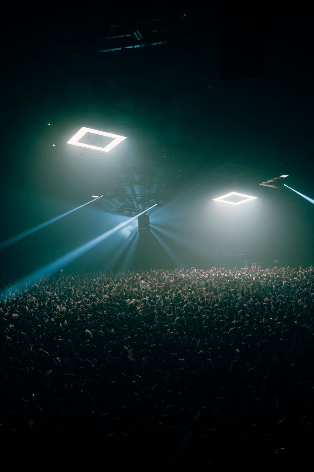 Square lighting panels cast ethereal glow over massive concert crowd.