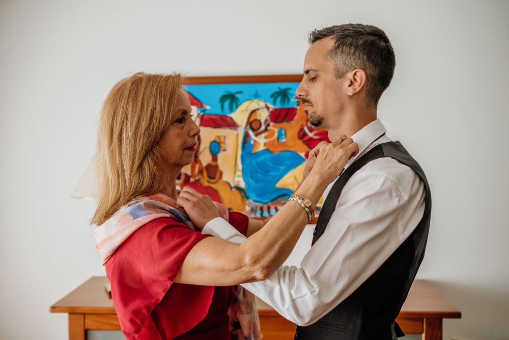A playful moment shared between a couple dressed in formal wear with a colorful painting in the background.