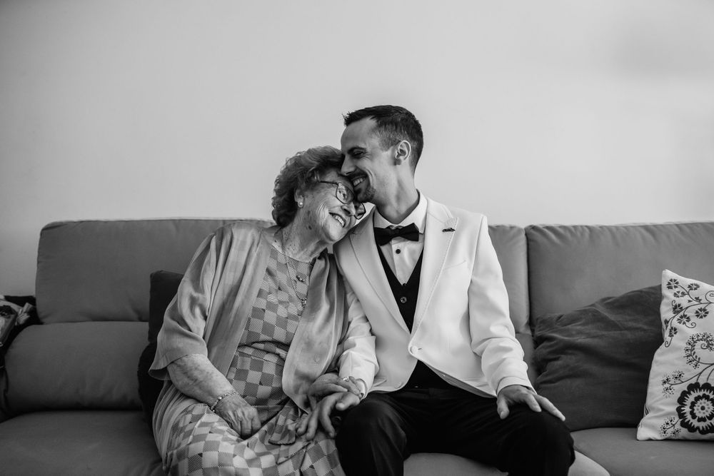 A tender black and white moment shared on a gray couch with decorative throw pillows.