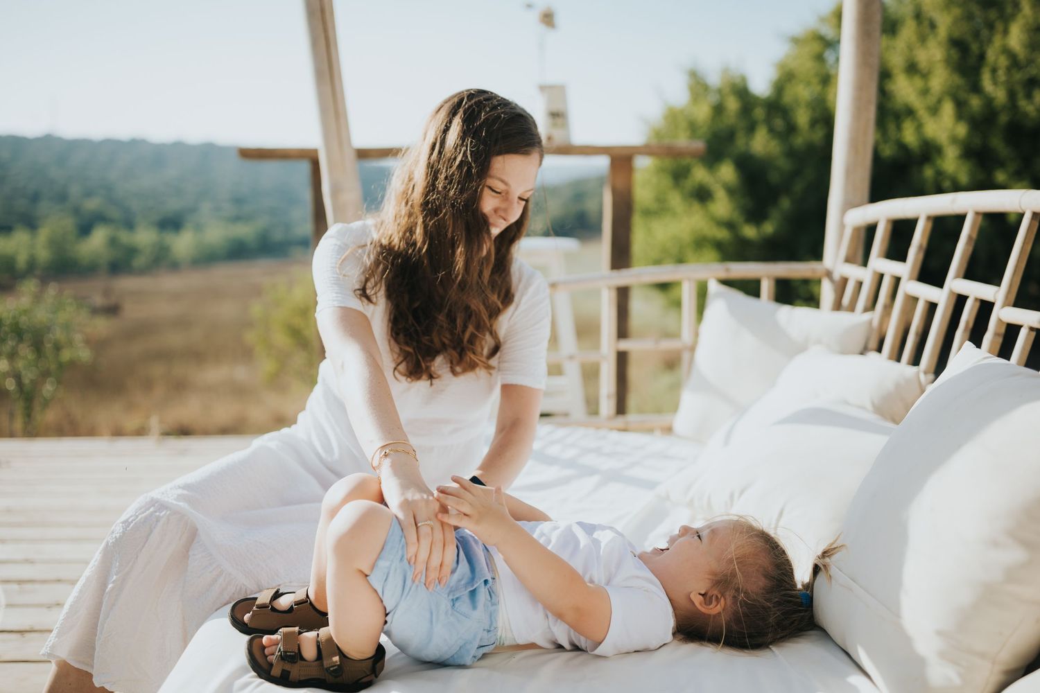 Mother and child playing together on outdoor deck with scenic background.