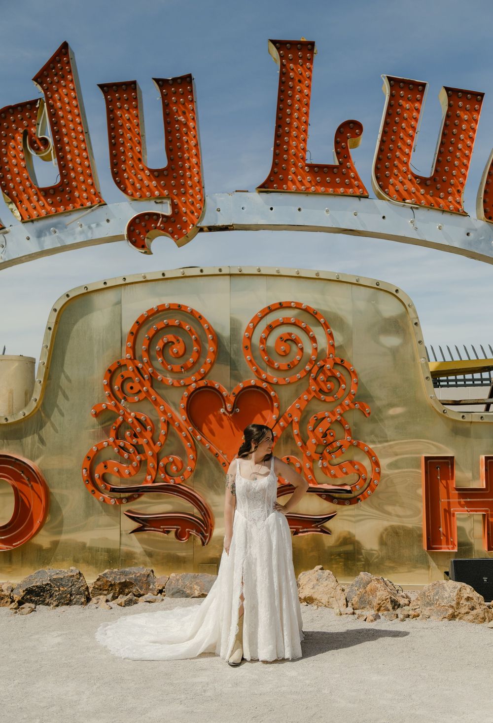 Bride in white gown poses at the Neon Museum in Las Vegas before a vintage Lady Luck sign.
