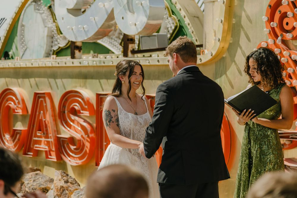 Couple exchanging vows at a Las Vegas wedding ceremony with vintage neon casino signs backdrop.