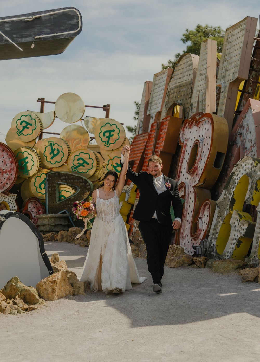 Bride and groom celebrate at the Neon Museum in Las Vegas, surrounded by colorful vintage signs.