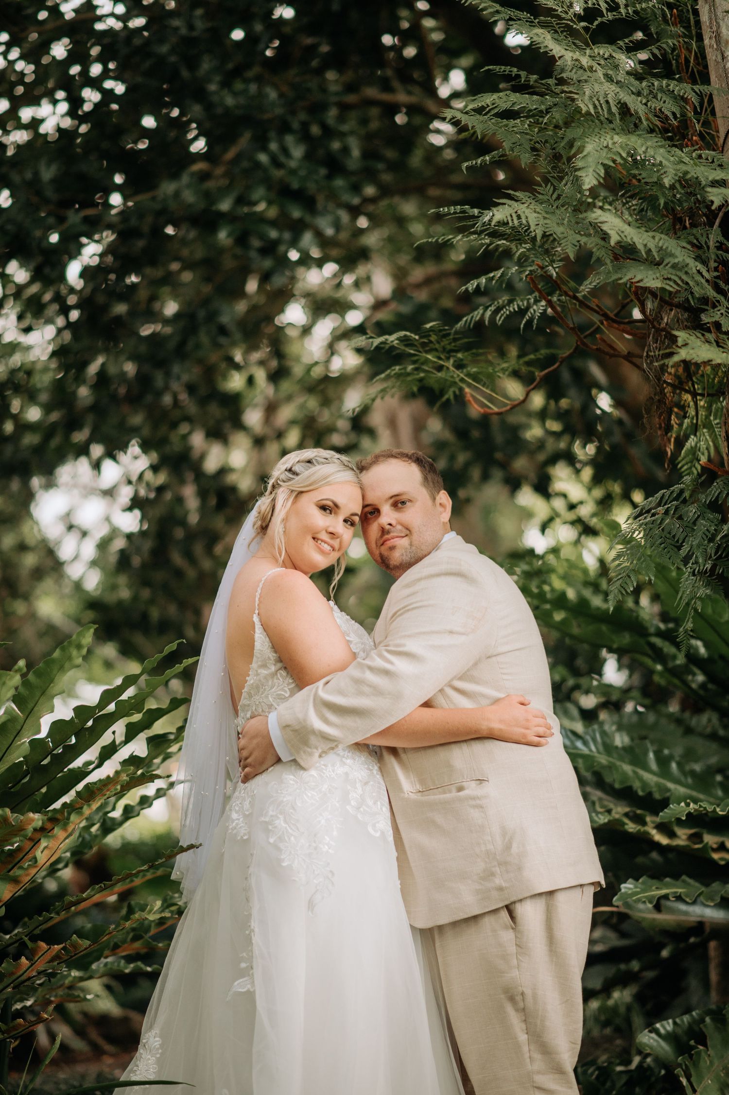 A tender wedding embrace captured in a lush garden setting with soft natural lighting.