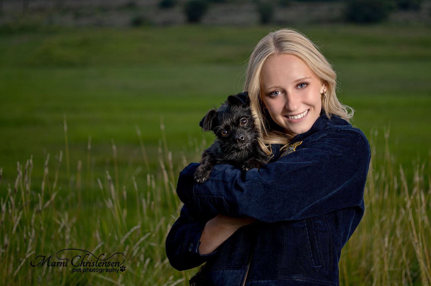 Portrait in outdoor field setting with small dog and blue denim jacket.