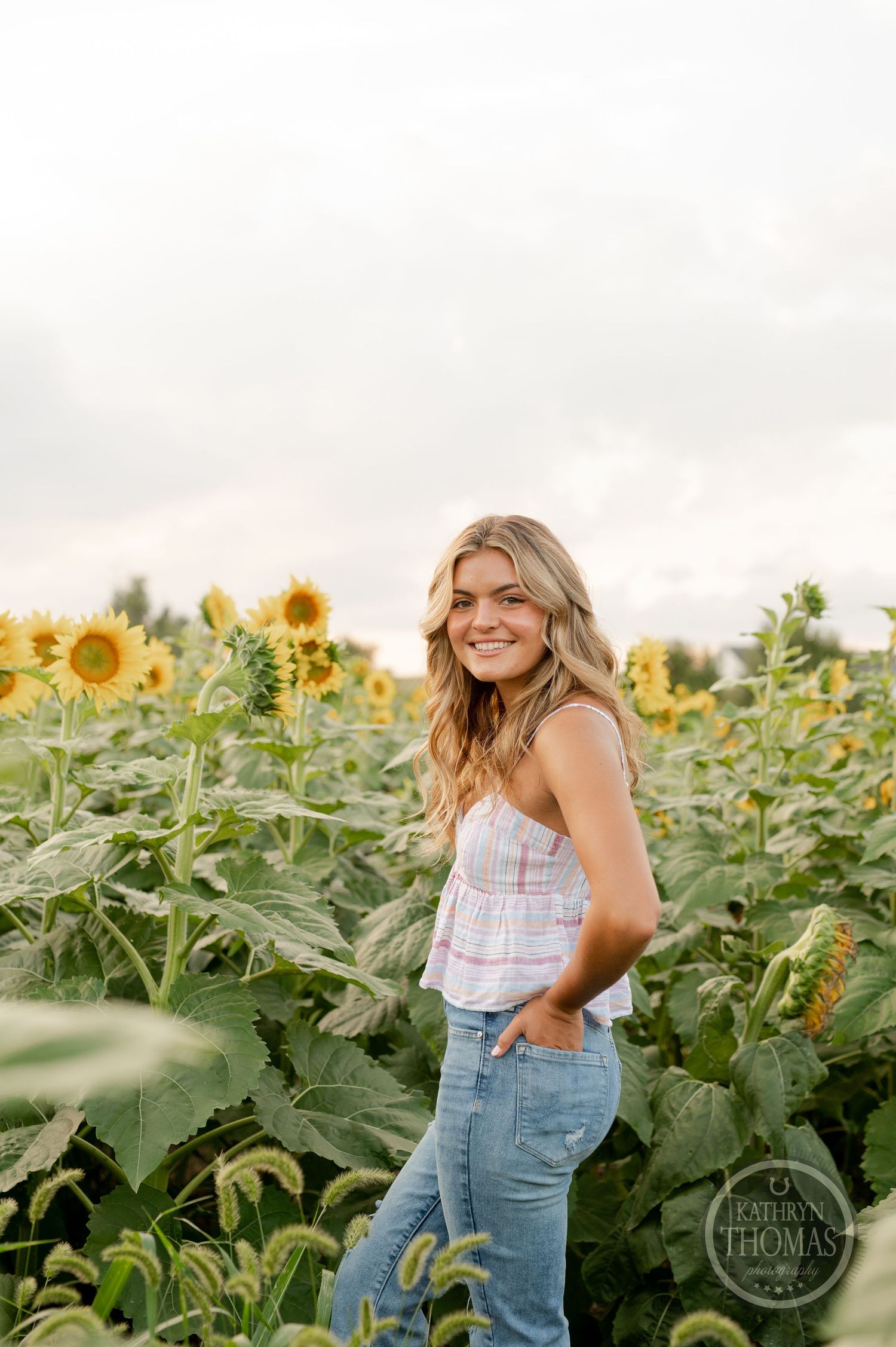 Casual outdoor portrait among tall sunflowers with warm evening lighting and natural scenery.
