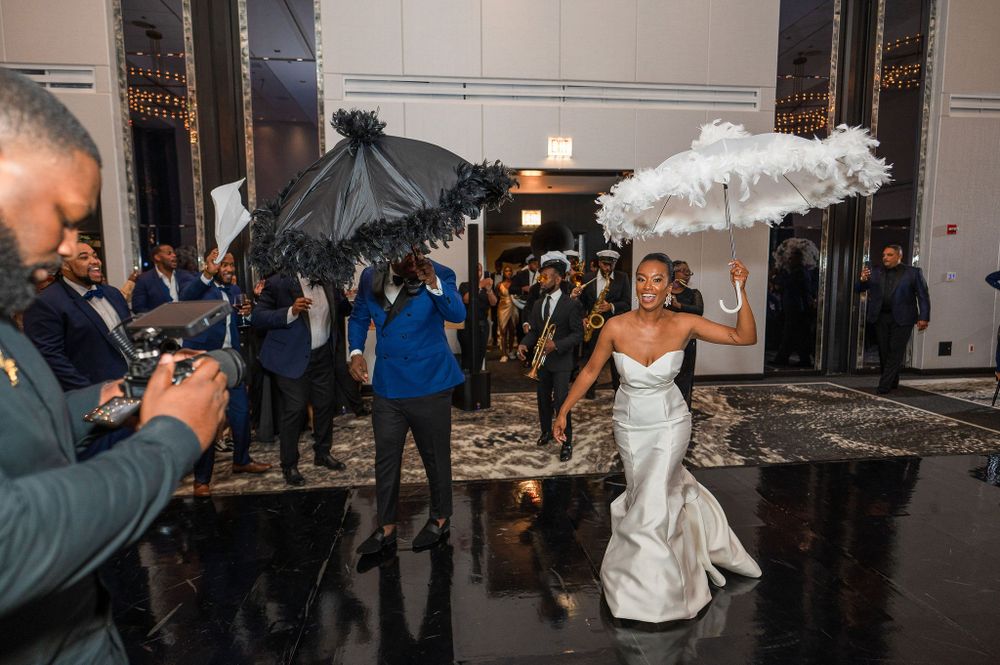 Wedding celebration with decorative umbrellas as guests dance on a reflective floor.