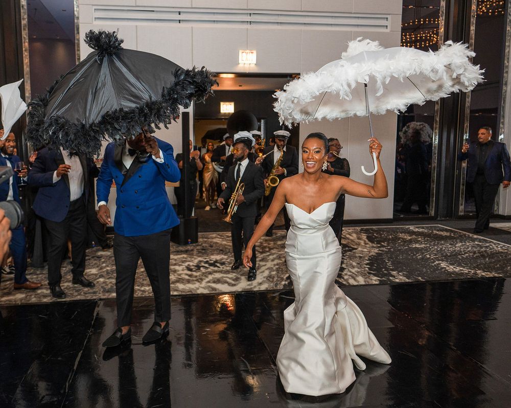 A joyful dance celebration with black and white decorative parasols at a wedding reception.