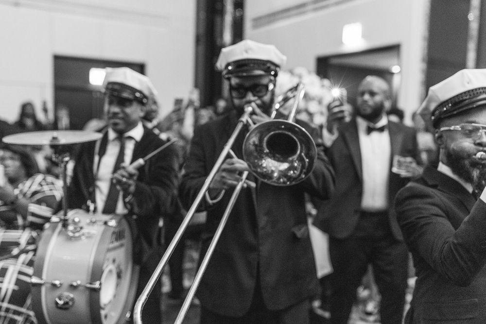 Black and white photo of a brass band performing with trombones and drums.