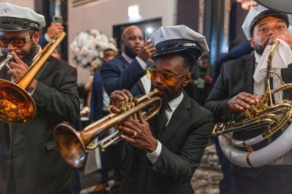 Jazz band musicians perform on brass instruments while wearing vintage-style caps and suits.