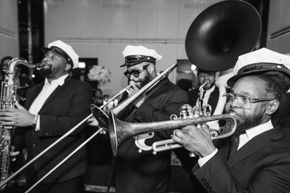 Black and white photo of brass band musicians performing with trumpets and trombones.