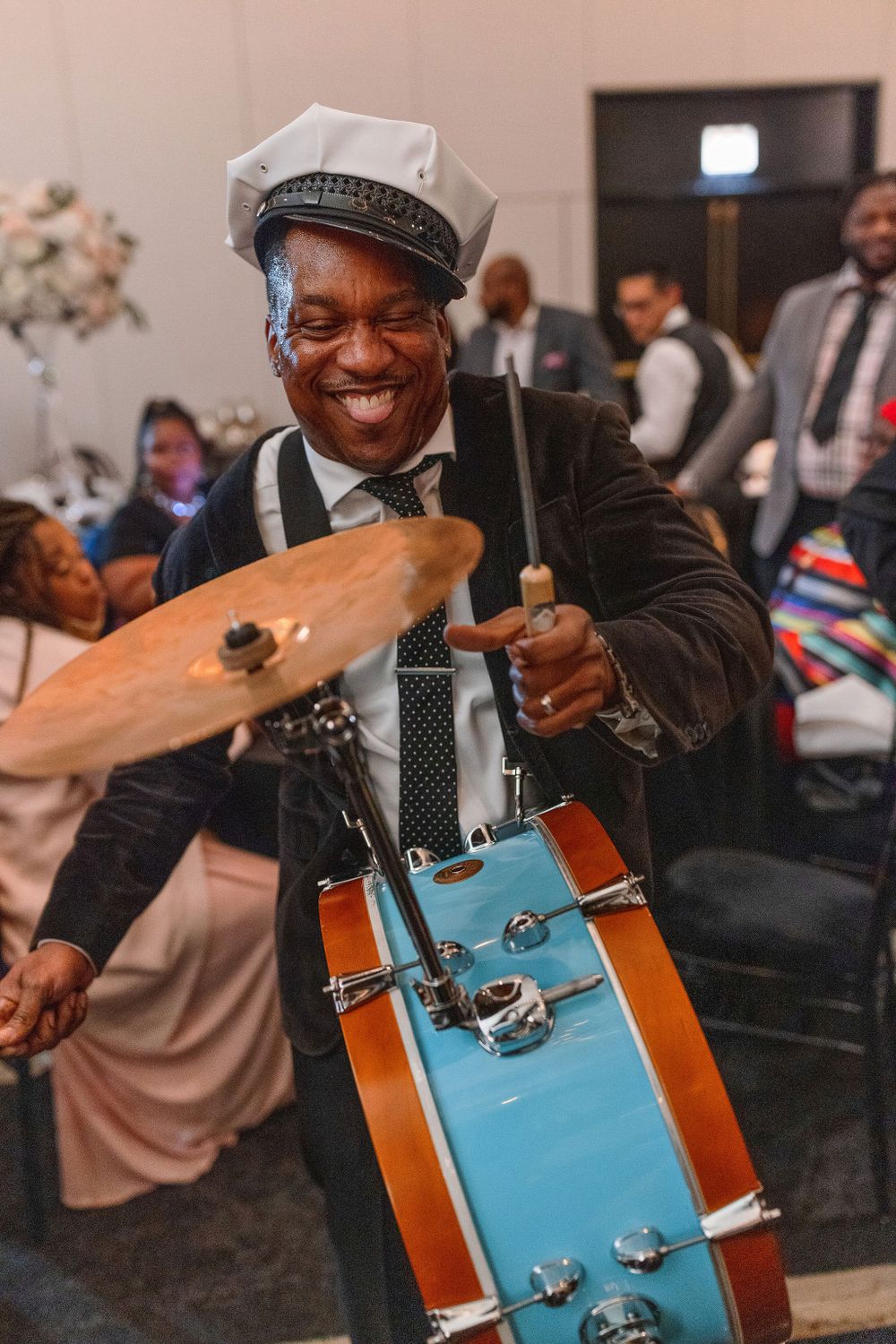 Musician plays bright blue drum set while performing at wedding reception.