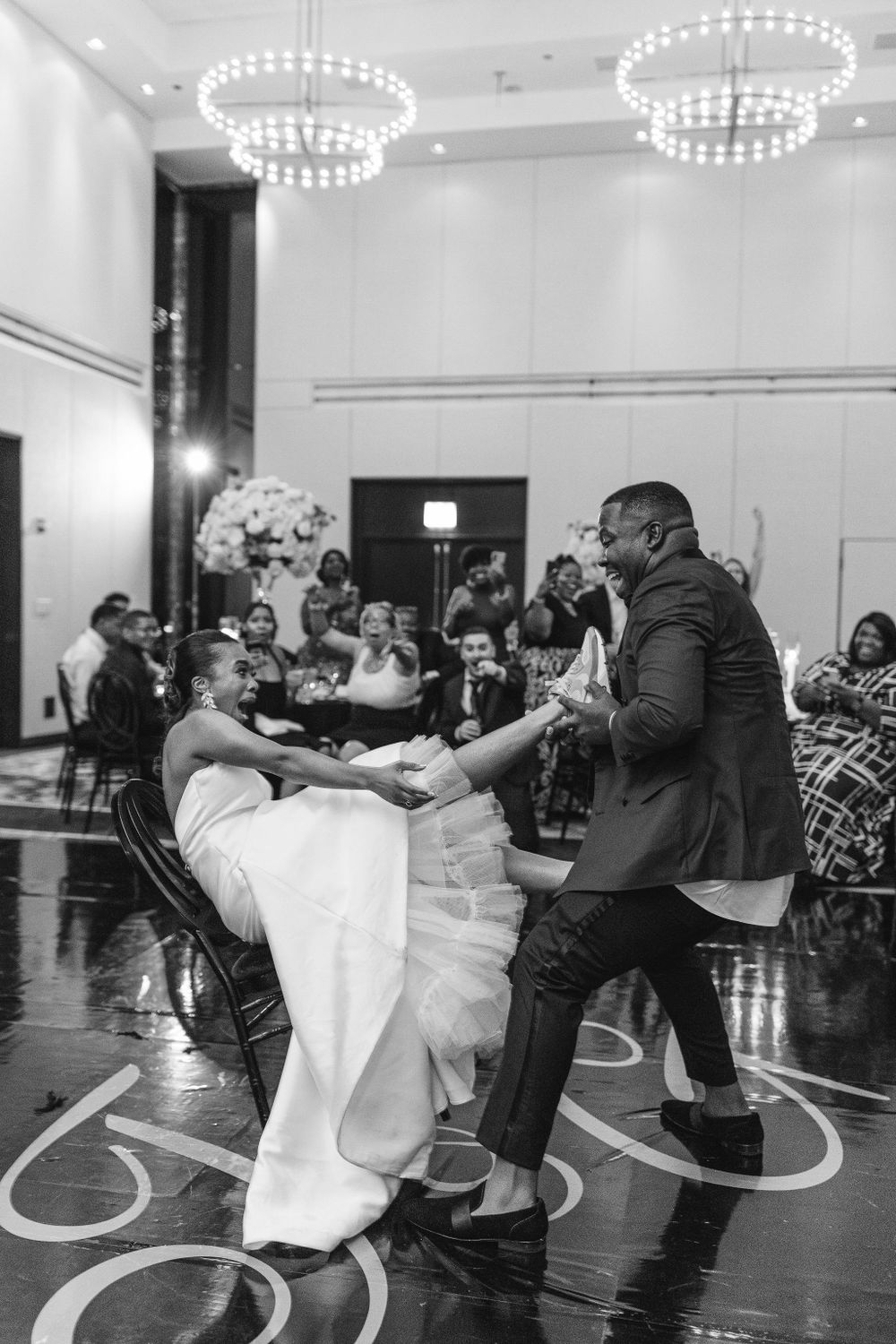 Black and white photo captures dynamic dance moves during a wedding reception.