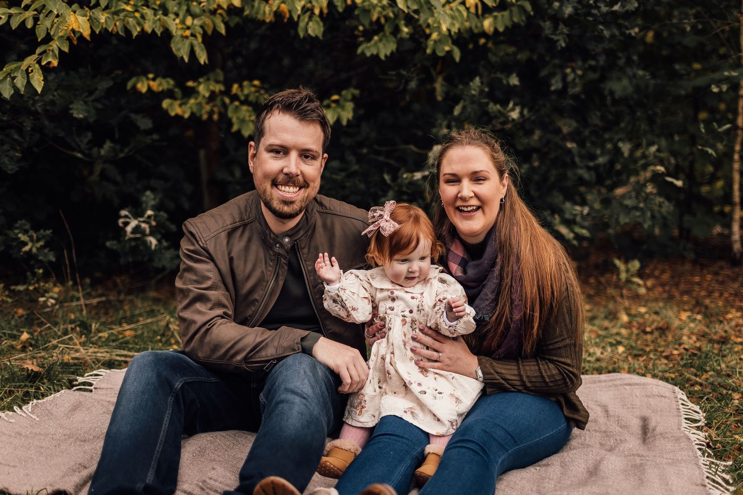 A candid autumn photography session in a wooded area with fallen leaves.