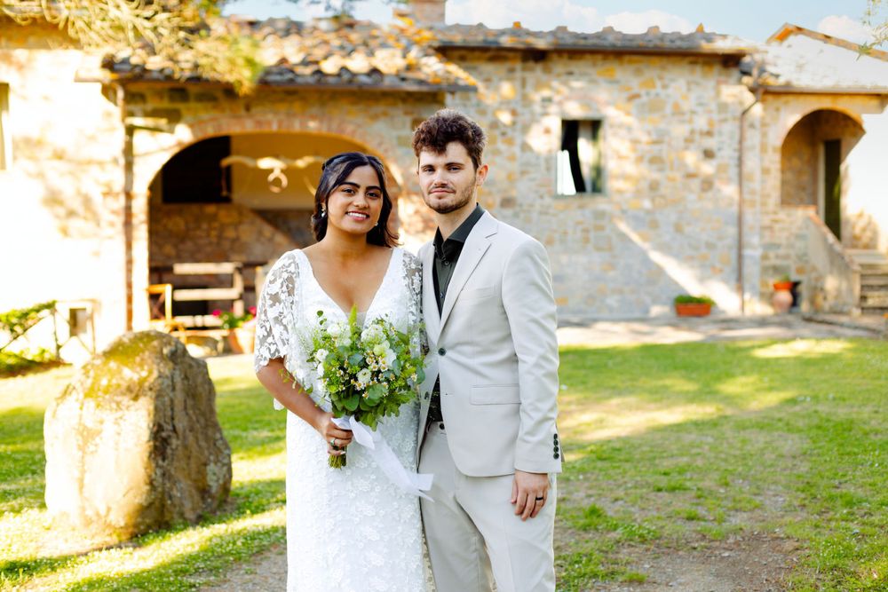 Wedding couple shares intimate moment outside historic Italian villa with stone walls.