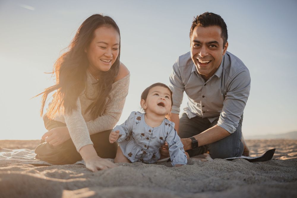 A joyful family plays together on a sandy beach at sunset.