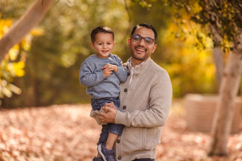 Father and child sharing joyful moment together during autumn outdoor photoshoot.