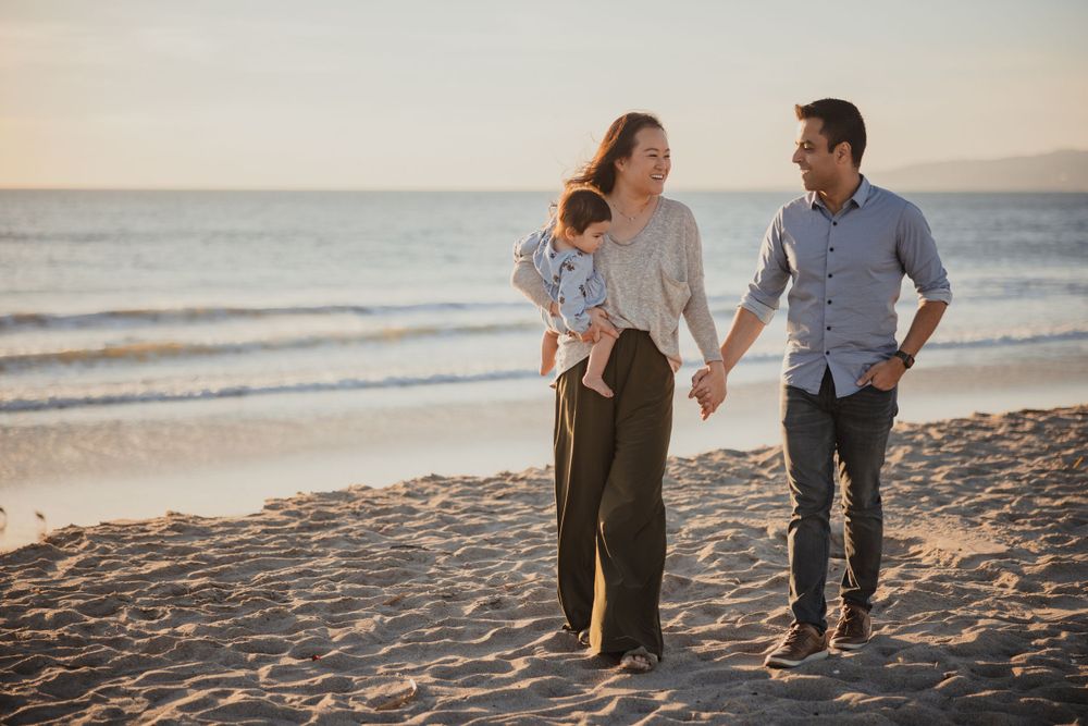 A couple walks hand in hand on a peaceful beach at dusk.