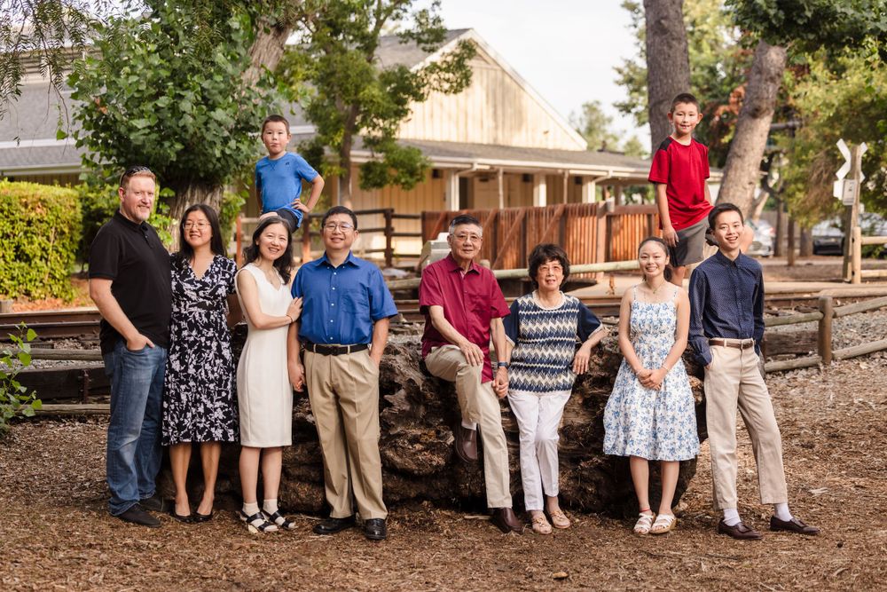 A family group poses together near wooden railroad tracks in casual attire.