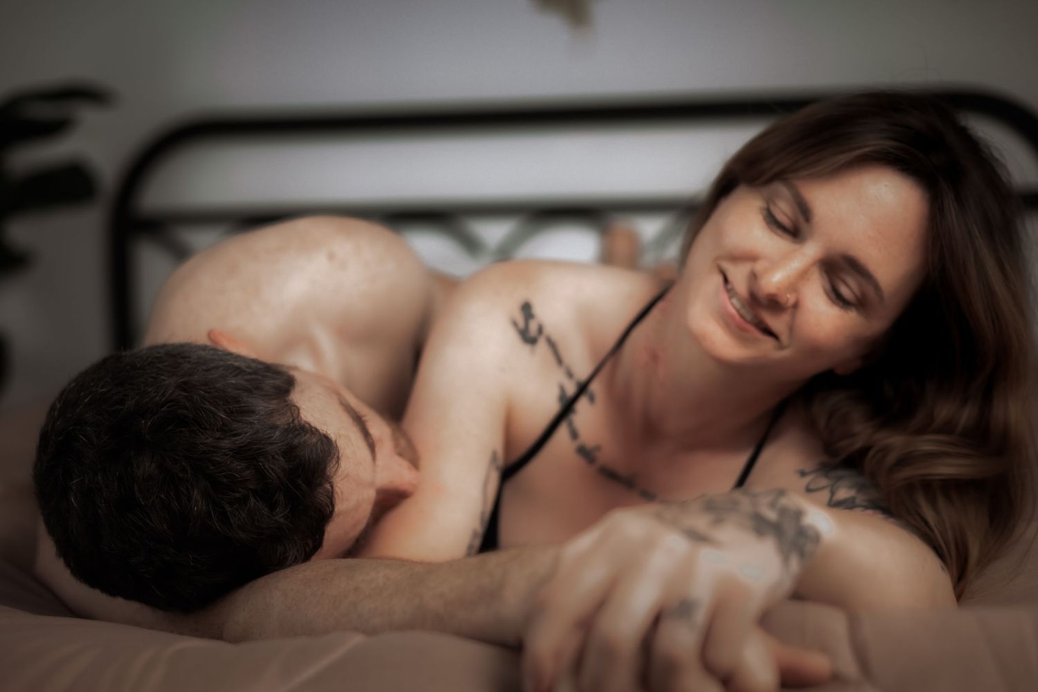 Intimate boudoir portrait of couple on bed in soft focus.