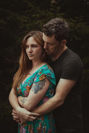 An intimate embrace showing off tattoos and a vibrant teal floral dress.