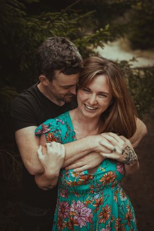 A joyful moment captured between two people in a wooded setting.