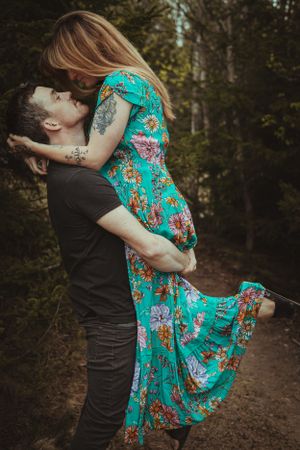 A couple dancing together on a forest path, her dress flowing with movement.