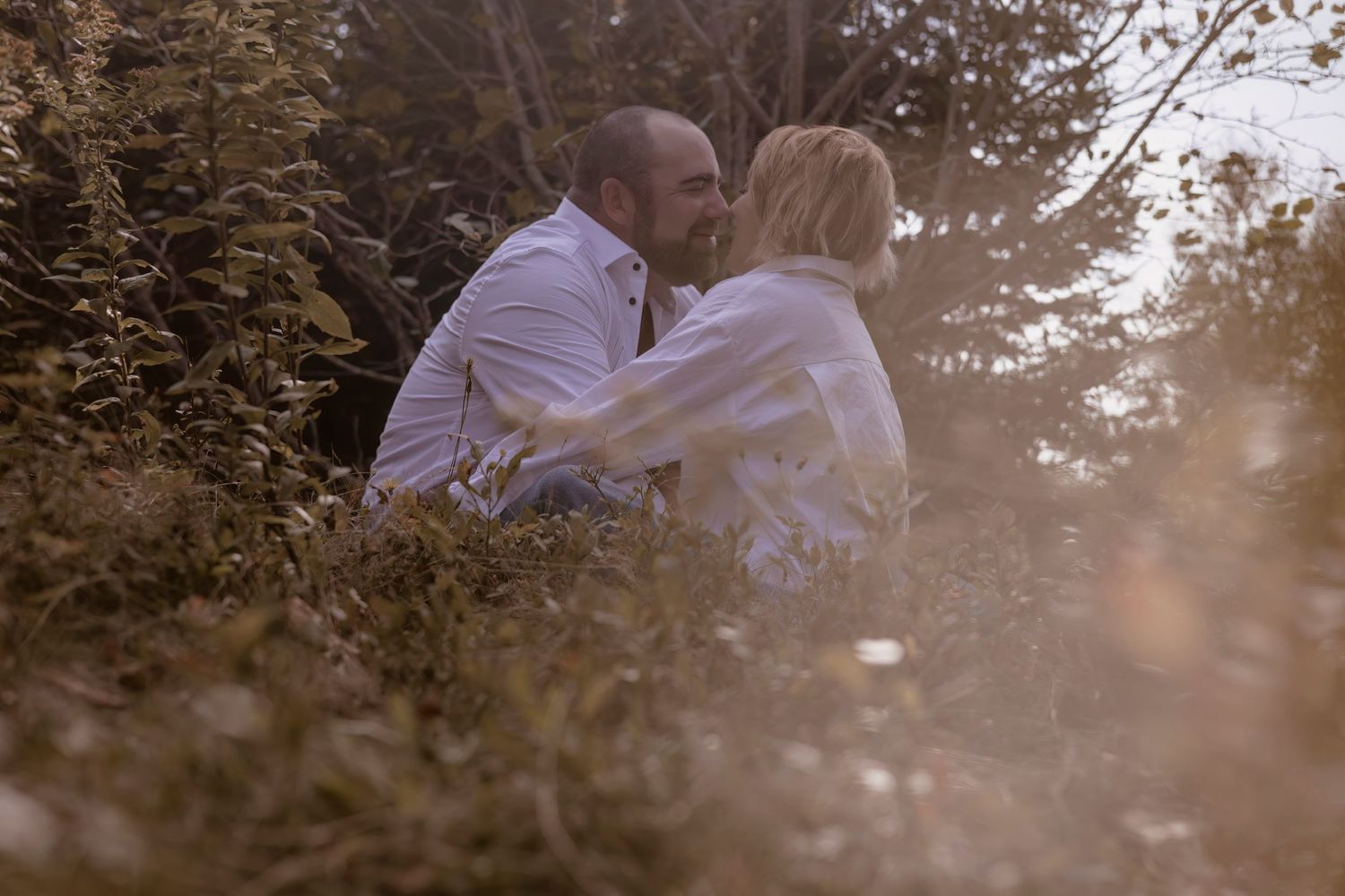 Couple sharing tender moment on hillside during golden hour.