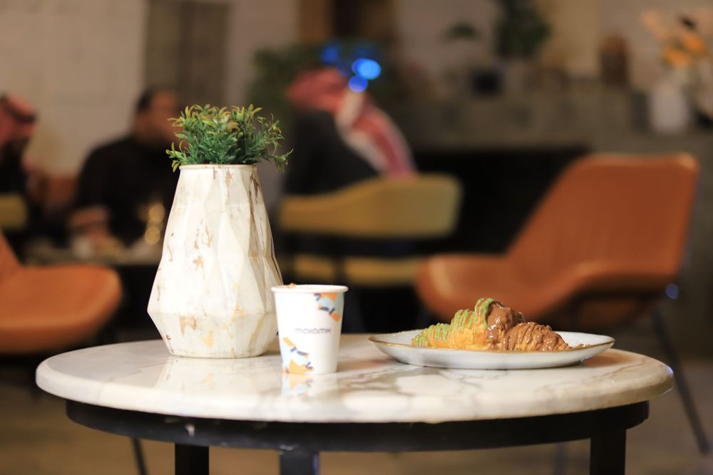 كوب من قهوة اللاتيه مع كروسان بصوص الشوكولاته والبوستاشو على طاولة التقديم