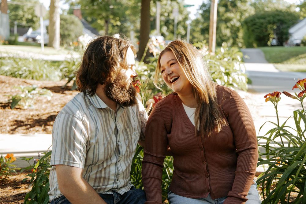 A couple shares a lighthearted moment while sitting together outdoors.