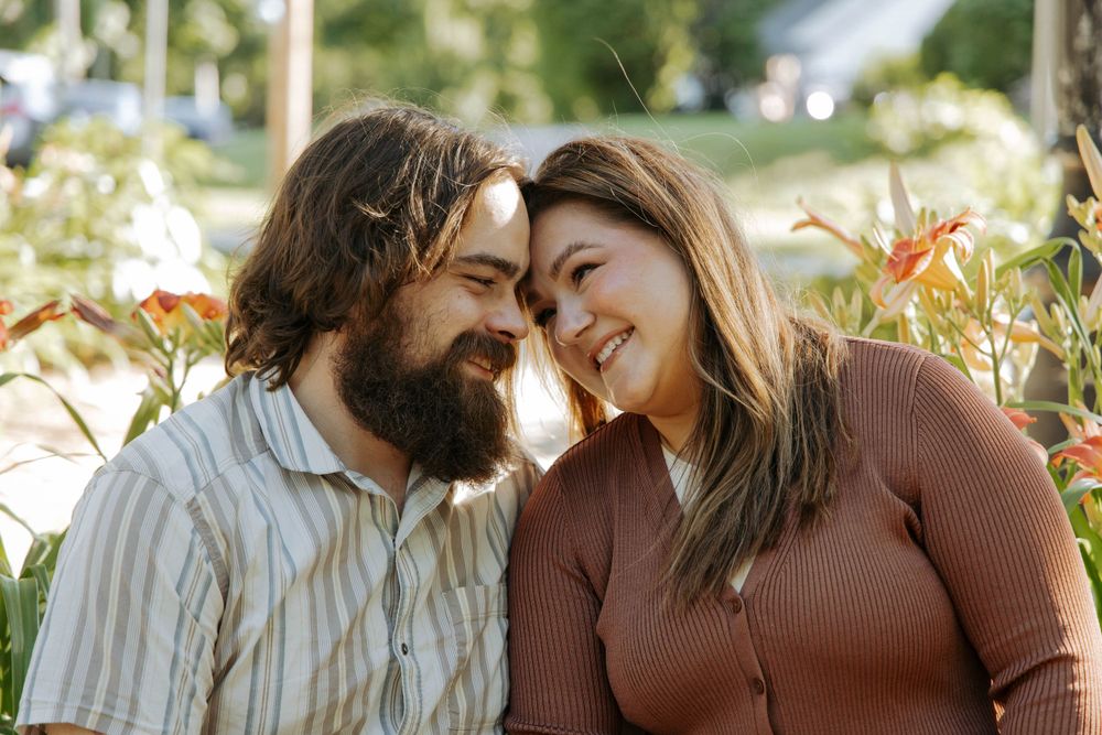 A couple shares an intimate moment while sitting together in a garden setting.