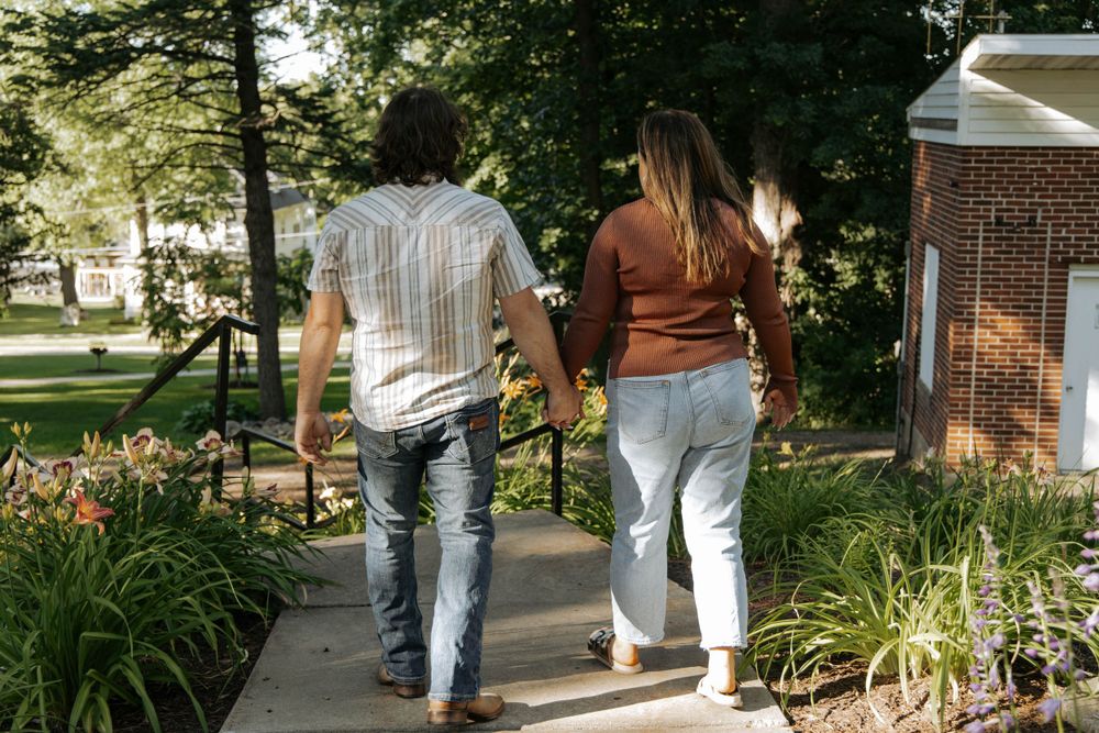 A couple walks together on a garden path surrounded by lush greenery.