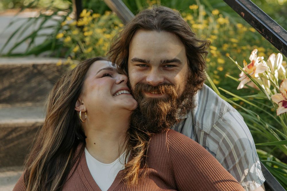 A couple shares joyful laughter while posing together outdoors.
